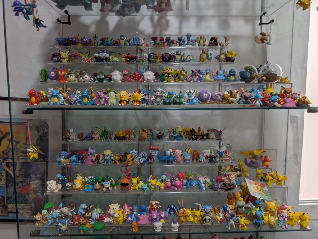 Varios estantes de acrílico de 4 peldaños, con figuras pequeñas detrás y figuras más grandes delante